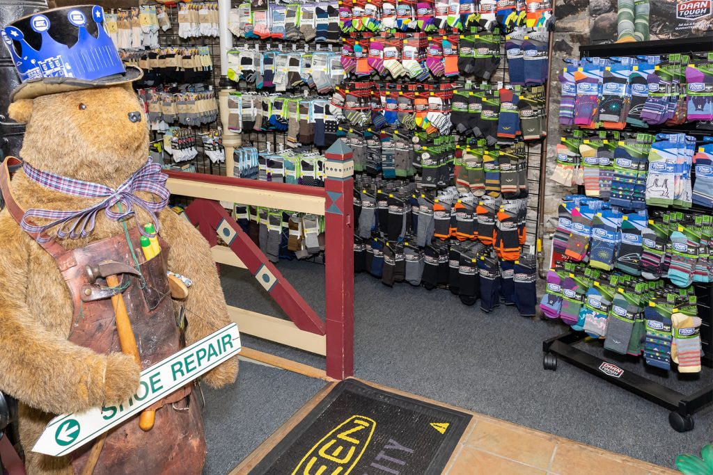 Shoe Repair Bear in front of wall of socks